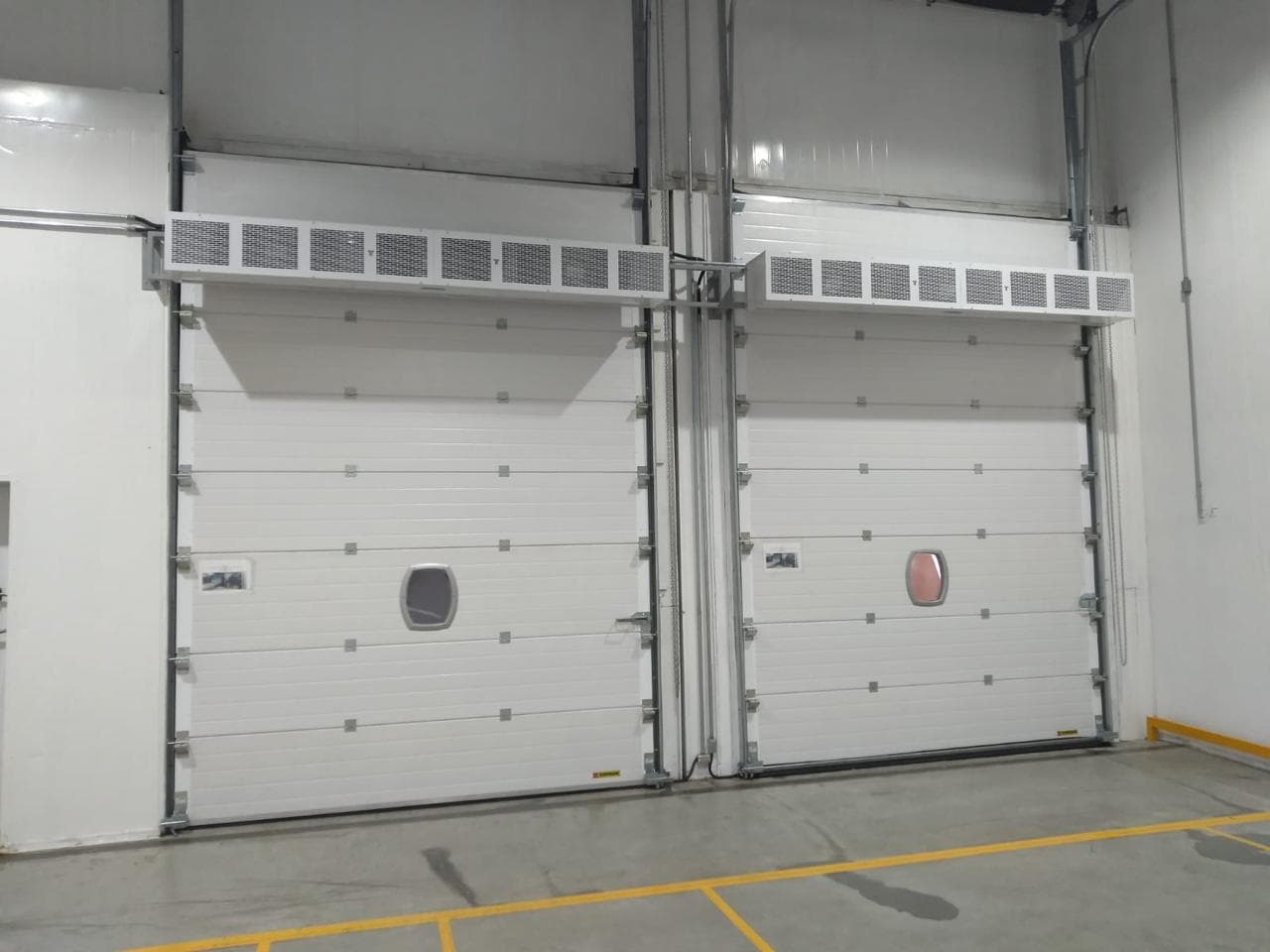 Duas cortinas de ar industriais instaladas sobre grandes acessos de uma área logística