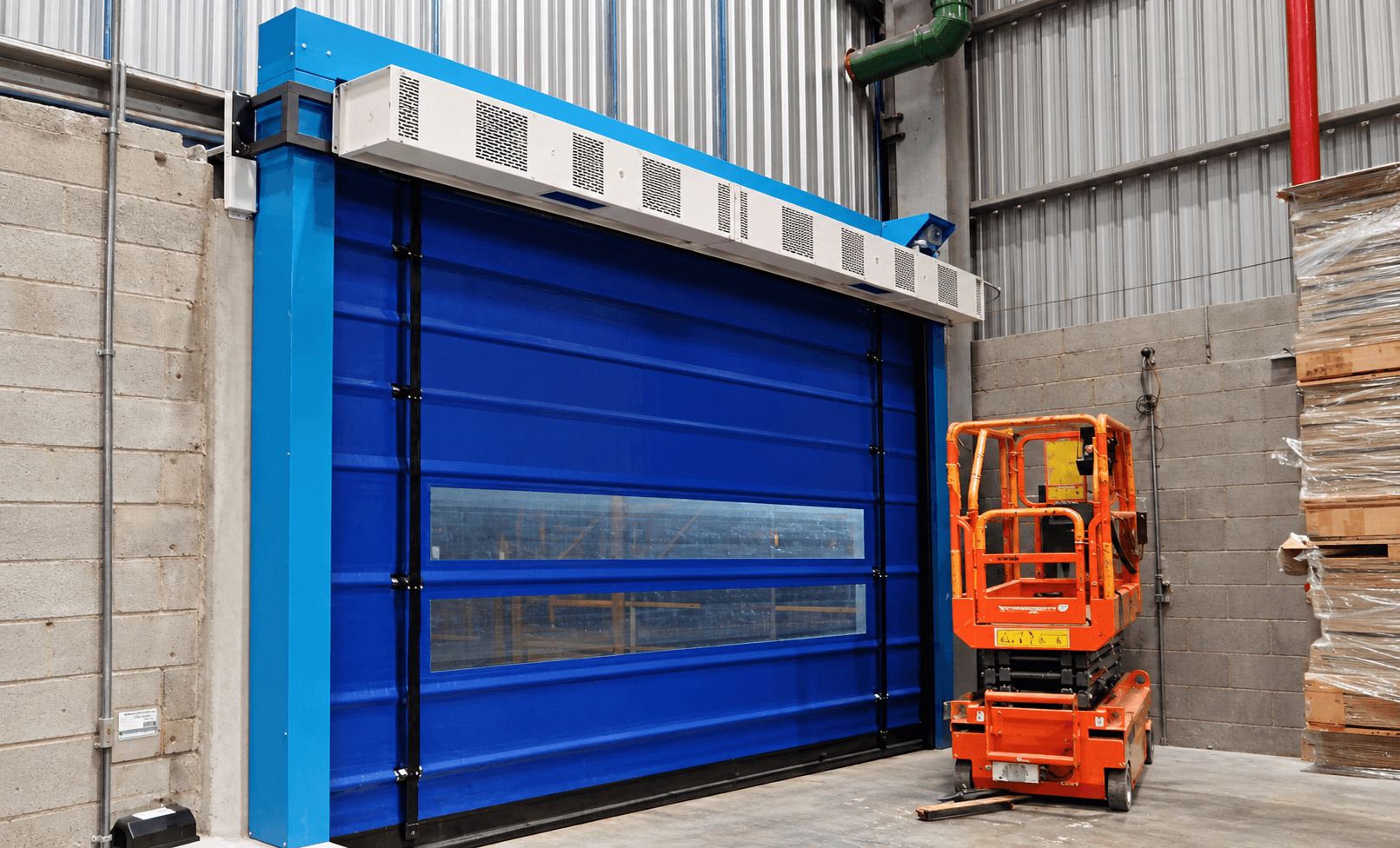 Cortina de ar industrial instalada sobre porta rápida azul em fábrica