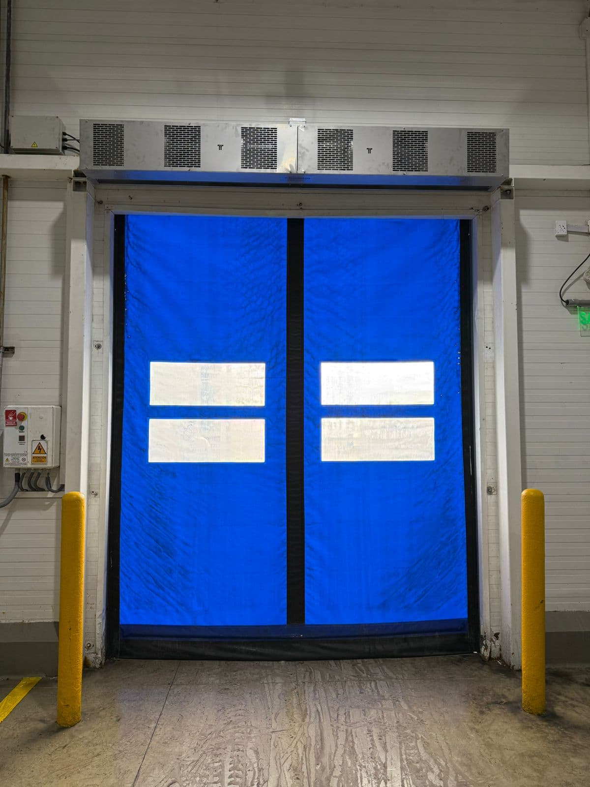 Cortinas de ar metálicas acima de porta rápida azul com visores