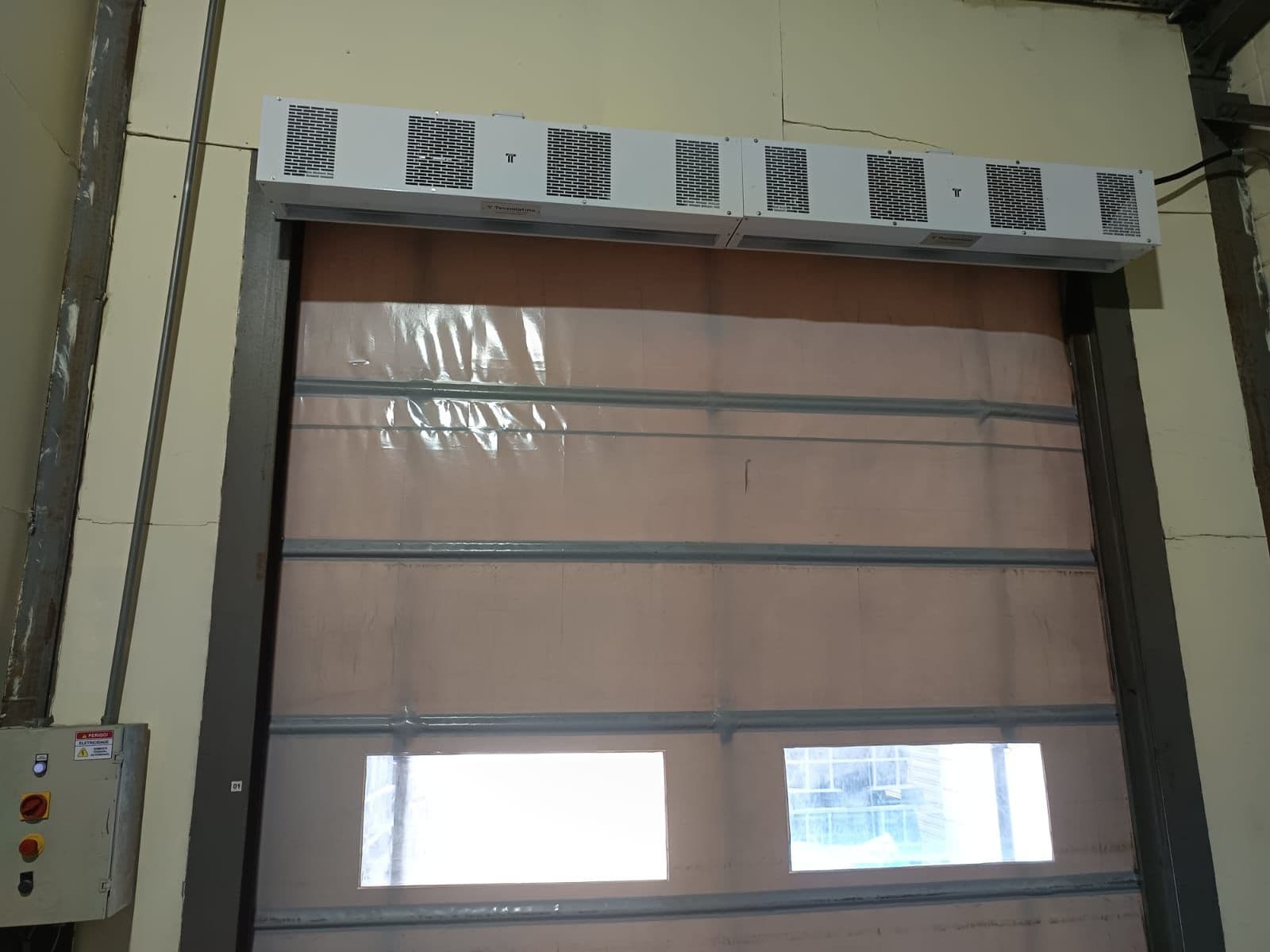Duas cortinas de ar brancas instaladas acima de porta flexível com visores