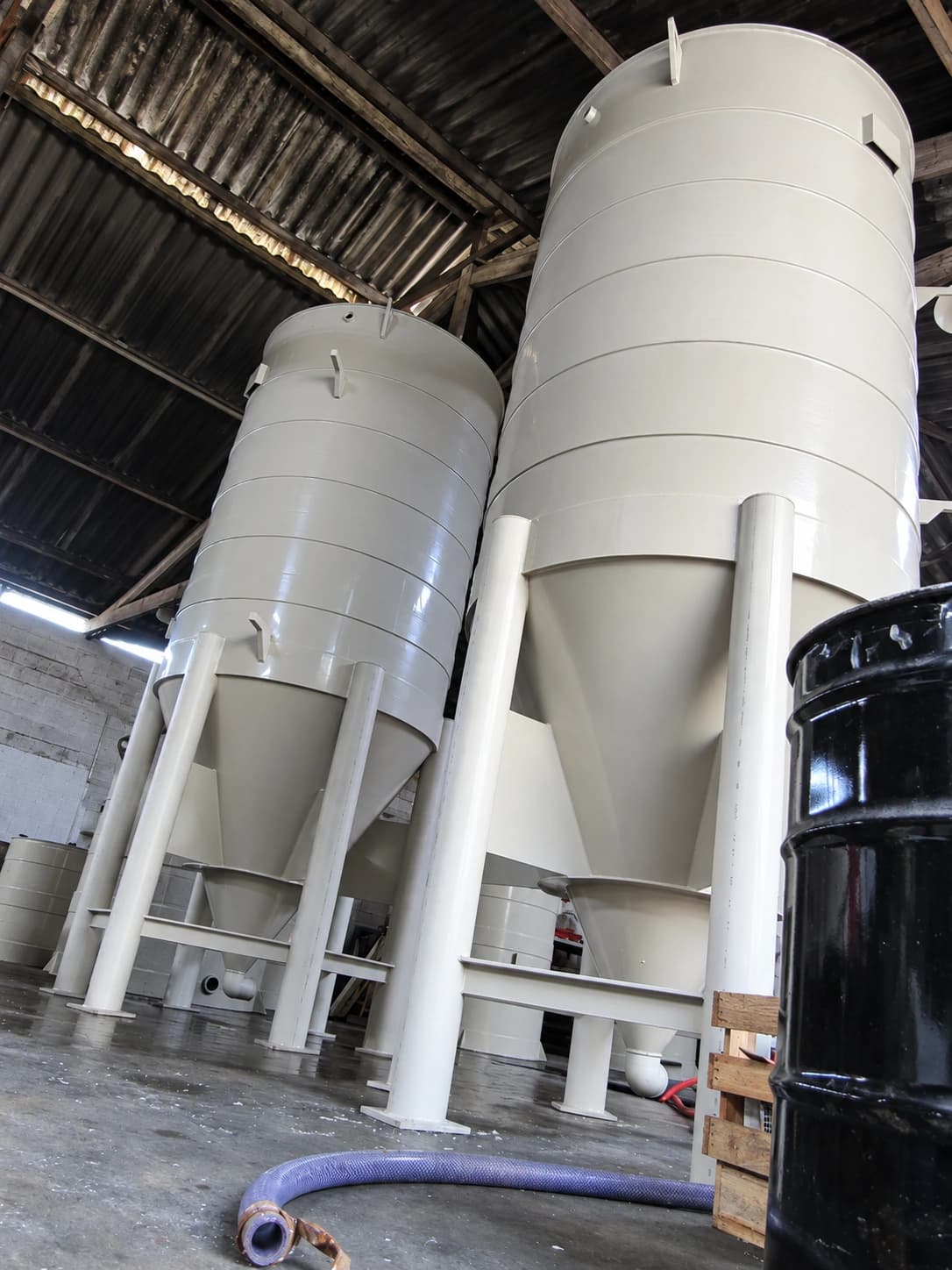 Tanques industriais cilíndricos com fundo cônico em área de fabricação